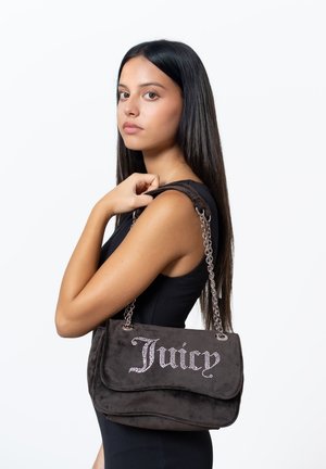 Braune Wildleder-Schultertasche mit einer Kettenriemen, die auf der Vorderseite "Juicy" in Strasssteinen zeigt. Weiche Textur, Klappen-Design und strukturierte Form.