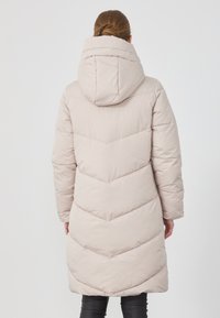 Lys beigefarget pufferjakke med hette, med chevron-quilting og lange ermer, som når midt på låret, laget av mykt, isolert materiale.