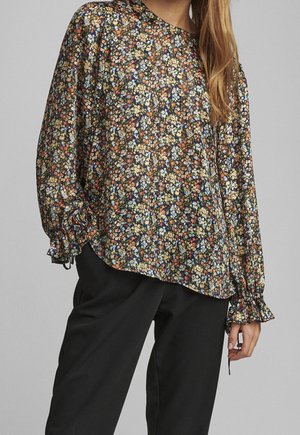 Blouse à manches longues florale en tissu sombre avec un fond noir. Comprend des manches bouffantes avec des poignets élastiques, délicats motifs floraux dans plusieurs couleurs.