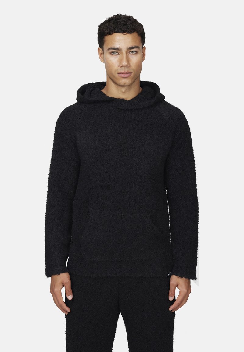 Felpa nera con cappuccio realizzata in materiale testurizzato e peloso. Presenta una tasca frontale e maniche ampie, abbinata a pantaloni coordinati.