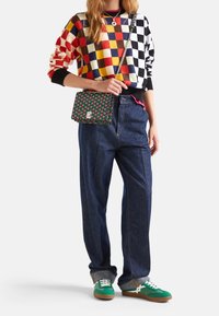 Färgglad rutmönstrad tröja, blå jeans och gröna sneakers med vita detaljer. Innehåller en mönstrad väska med kedjestrap.