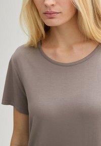 Kortärmad t-shirt med rund hals i ljus taupe, tillverkad av mjukt tyg. Har en enkel design utan synliga mönster eller detaljer.