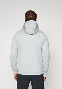 Light gray hoodie with a soft texture and a drawstring hood. Features a logo on the upper back and ribbed cuffs and hem.