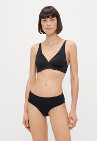 Conjunto de sujetador y braguitas a juego en negro, hecho de una tela suave con bordes festoneados. El sujetador tiene un diseño de escote en V, sin relleno y con tirantes ajustables.