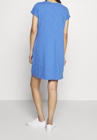 Blå kortärmad klänning med avslappnad passform, tillverkad av lätt tyg, med en subtil textur och en rak nederkant.