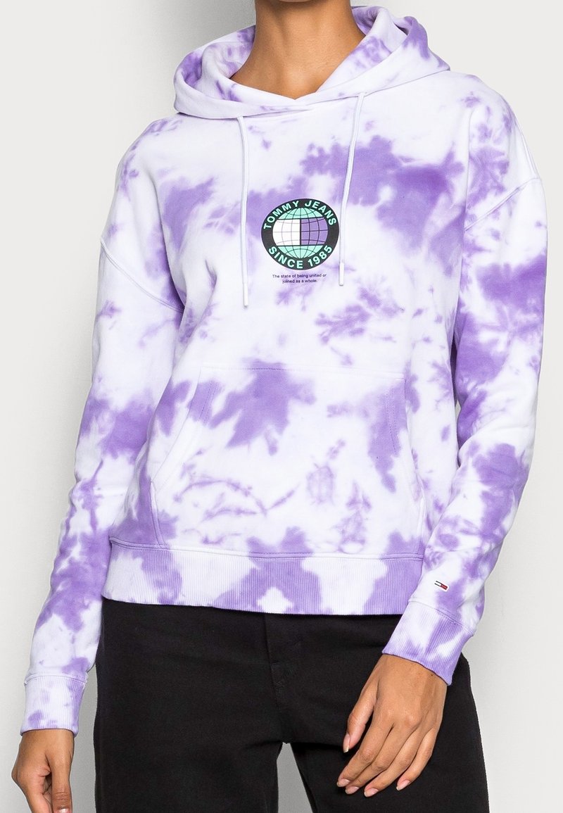 Lavender tie-dye hoodie with a large graphic circle logo on the chest, drawstring hood, front pocket, and ribbed hem and cuffs.