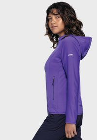 Lila Zip-Jacke mit Kapuze, strukturiertem Stoff, vertikalem Rippmuster und seitlicher Reißverschlusstasche. Figurbetonte Passform mit flachen Nähten.