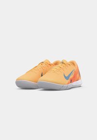 Oranžid sportlikud kingad tekstuuriga pealsega, millel on sinine Nike logo ja erksad punase-oranži aktsentdisain külgpinnal. Valge põhjaga.