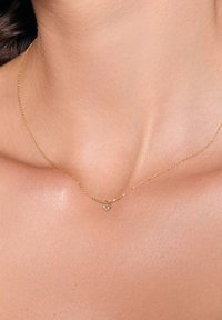 Delikatny złoty naszyjnik z małym diamentowym wisiorkiem, z cienkimi skręconymi ogniwami i minimalistycznym wzornictwem.