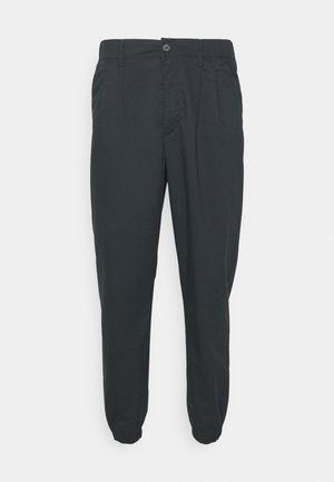 Schwarze Hose mit schmal zulaufendem Bein, elastischen Bündchen, Seitentaschen und Knopfverschluss; aus leichtem Stoff mit glatter Textur.