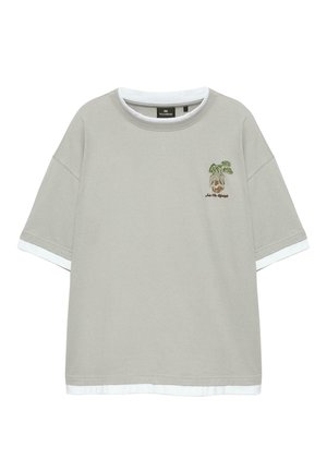 T-shirt gris clair à manches courtes avec ourlet et poignets blancs en couches, avec une petite plante verte et le texte marron "Into The Lifestyle" sur la poitrine.