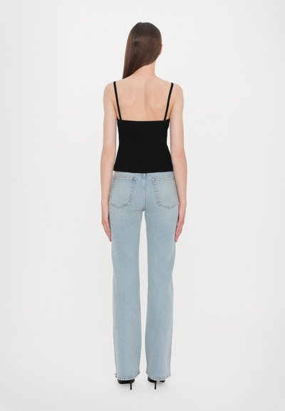 Black spaghetti-strap top paired with light blue flared jeans. The top has a fitted design, and the jeans feature standard back pockets.