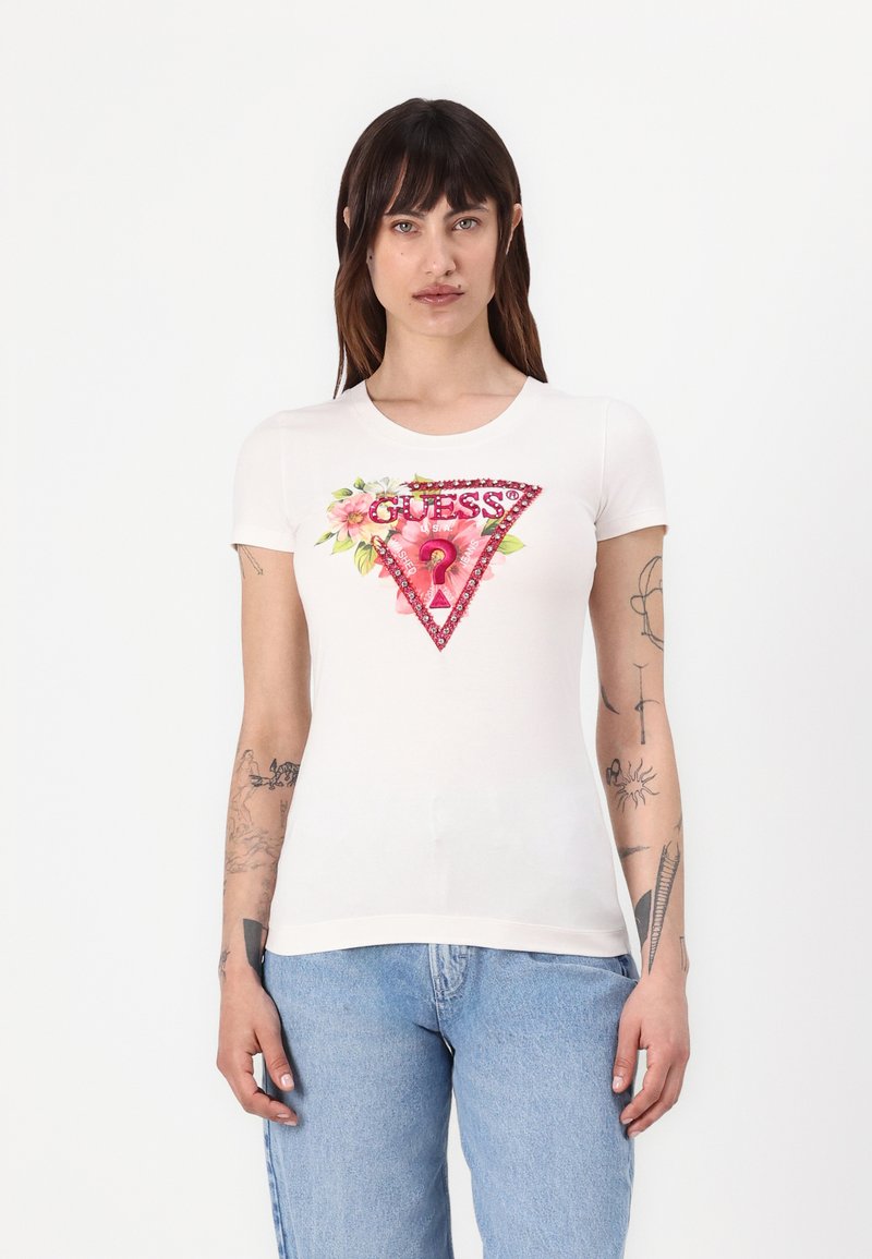Witte T-shirt met korte mouwen, met een driehoekig bloemmotief en "GUESS?" in het rood, versierd met pailletten aan de voorkant. Gemaakt van textuur katoen.