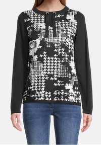Svart och vit mönstrad stickad sweatshirt med lång ärm, med rundad halsringning och dragsko-detalj vid kragen.