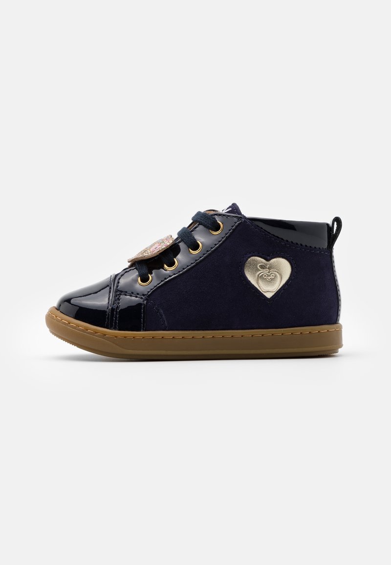 Chaussure bébé montante bleu marine avec semelle marron, lacets noirs, bout brillant et emblème cœur doré sur le côté.