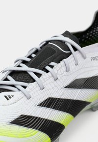 Scarpa da football con una tomaia bianca testurizzata e accenti neri e giallo neon, lacci grigi e un design elegante e aerodinamico.