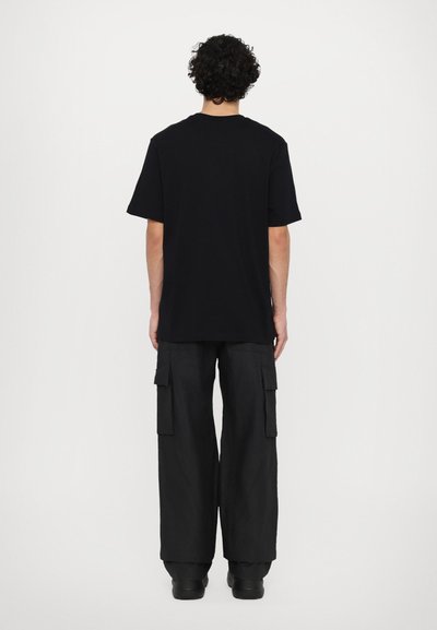 Black cotton t-shirt with short sleeves, relaxed fit, and a crew neckline, paired with loose black cargo pants featuring side pockets.
