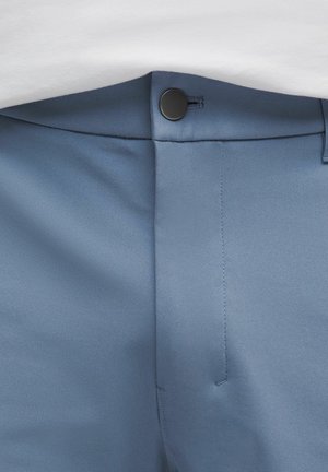 Helle blaue Hose aus glattem Stoff. Verfügt über einen Knopfverschluss, flachen Frontbereich und ordentliche Nähte entlang der Nähte.