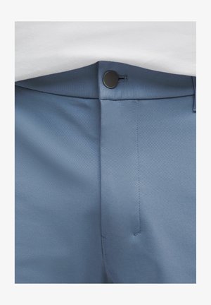 Pantalones azul claro hechos de una tela suave. Presentan un cierre de botón, un frente plano y costuras cuidadas a lo largo de las costuras.