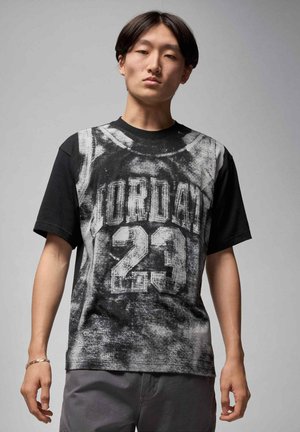 T-shirt a maniche corte nero e grigio con stampa grafica effetto usurato con la scritta "JORDAN" e il numero "23" in evidenza.