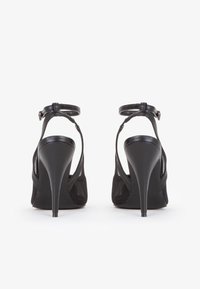 Sandalias negras de tacón alto con un diseño de tiras, material de cuero y tacones de aguja; cuenta con una correa en el tobillo con cierre de hebilla.