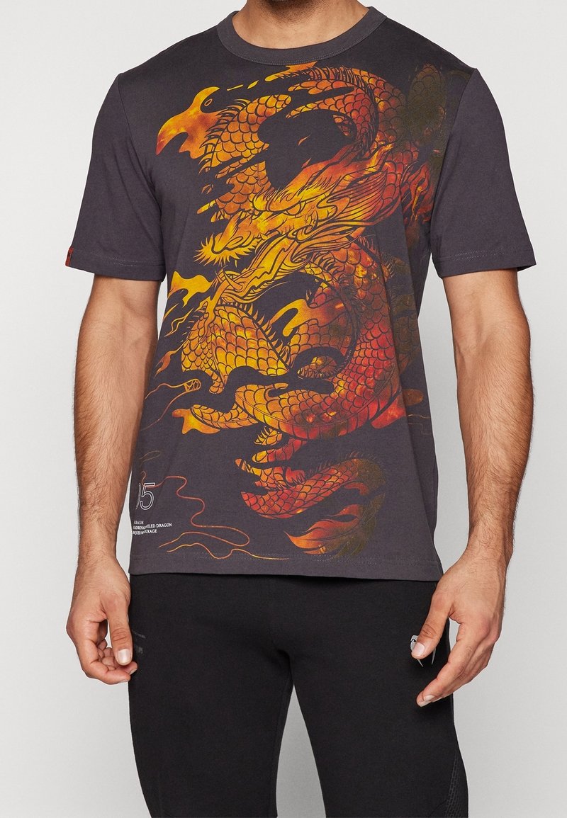 T-shirt en coton noir avec un graphisme audacieux de dragon rouge et jaune sur le devant, manches courtes et col rond.