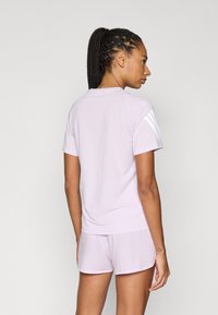Jasnofioletowa sportowa koszulka z krótkimi rękawami i zaokrąglonym dekoltem, w zestawie z dopasowanymi szortami o teksturowanym wzorze.