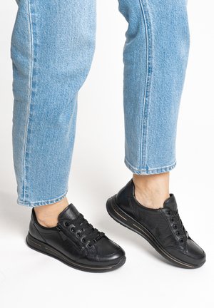 Black leather sneakers with textured panels, lace-up design, and rubber soles. Styled with cuffed blue jeans, showcasing a casual appearance.
