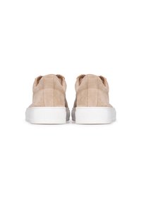 Zapatos slip-on de ante beige con suela blanca, que presentan un cuello texturizado y un diseño aerodinámico. Simples, sin adornos adicionales.