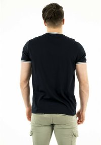 Polo de manga corta azul marino con ribete blanco en el cuello y las mangas, hecho de material de algodón suave, diseño ajustado, vista posterior.