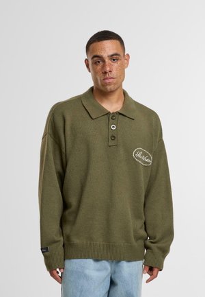 Olive green knit polo sweater with three buttons, ribbed cuffs, and an embroidered logo on the left chest. Soft texture, relaxed fit.