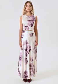 Bloemige tweedelige jurk van satijn, met een aangesloten crop top en een vloeiende maxi rok met grote paarse en witte bloemenpatronen.