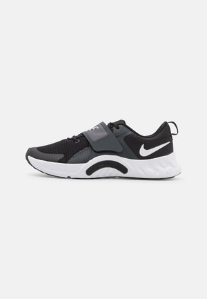 Chaussure de sport noir et gris avec tige en mesh, sangle ajustable, semelle blanche rembourrée et détails de semelle extérieure noire bien marqués.
