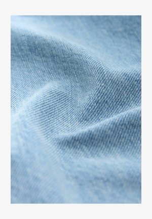 Tessuto di denim azzurro chiaro con una trama morbida e un motivo di intreccio visibile. Il materiale presenta pieghe e sottili variazioni di profondità.