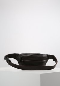 Schwarze Leder-Umhängetasche mit einem eleganten Design, die über ein Hauptfach und eine vordere Reißverschlusstasche verfügt, einen verstellbaren Gurt und eine glatte Textur aufweist.