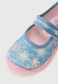 Zapato de color azul claro con diseño de copos de nieve, suela de goma rosa y correa ajustable. Acabado de tela texturizada con acentos de purpurina.