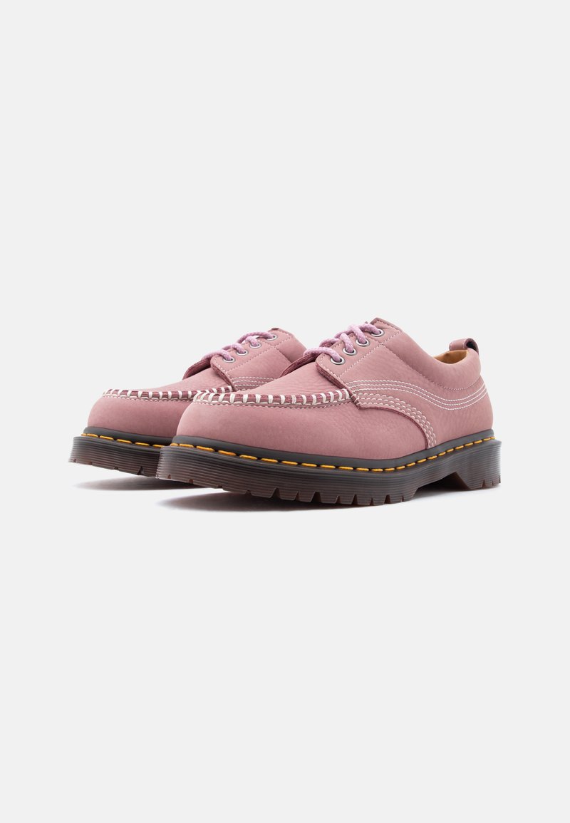 Coppia di scarpe stringate in pelle rosa con suole nere spesse e cuciture gialle, mostrate su uno sfondo bianco semplice.
