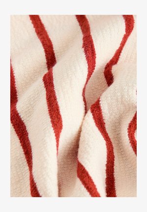 Serviette rayée en crème et rouge profond, présentant un tissu doux et texturé avec des rayures larges et étroites alternées.