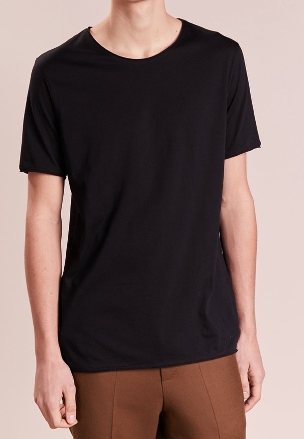 Camiseta negra de manga corta hecha de un tejido suave y liso con un cuello redondo. Combinada con pantalones marrones de corte ajustado y diseño minimalista.