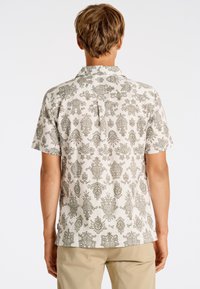 Korte mouw shirt van lichtgewicht stof, beige met een ingewikkeld groen bloemenpatroon, klassieke kraag en plooidetail op de rug.