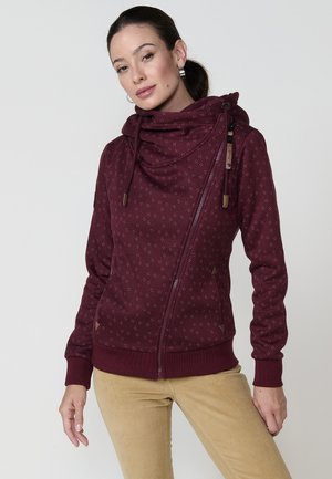 Sudadera con cremallera en color burdeos, con cuello tipo cowl, tejido texturizado con pequeñas motas, cremallera lateral y detalles de cuero en los cordones.