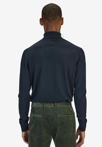 Mörkblå långärmad polo med ribbat krage, kombinerad med olivgröna manchesterbyxor med bakfickor och lätt struktur.