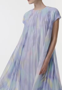 Vestido de color púrpura claro con un diseño plisado, mangas cortas tipo capa y suaves patrones en tonos pastel de azul, amarillo y verde. Textura de tela translúcida.