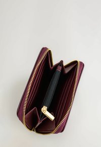 Portafoglio in pelle bordeaux con zip dorata. Presenta diversi scomparti per carte, un compartimento con zip nera e una superficie testurizzata. Vista aperta.