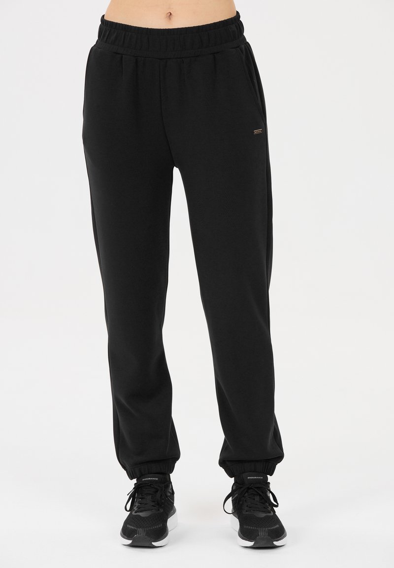 Zwarte trainingsbroek met een elastische tailleband, tapse enkelboorden en zijzakken. Gemaakt van zachte stof met een subtiele textuur. Minimalistisch ontwerp.