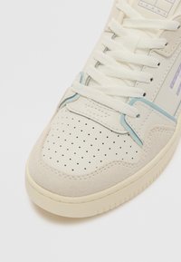 Beige sneaker with perforated leather and suede. Light blue accents on side. Thick cream laces and rubber sole. Rounded toe design.