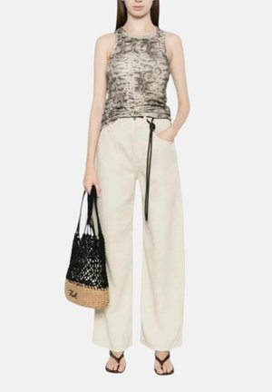 Donna che indossa un top senza maniche con stampa animalier, pantaloni beige larghi a vita alta con cintura nera, tiene una borsa nera intrecciata e indossa sandali neri.