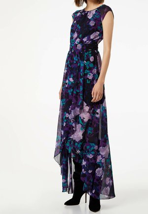 Robe maxi avec un motif floral en violet et turquoise, fabriquée en tissu léger. Ourlet asymétrique et manches courtes. Accents noirs visibles.