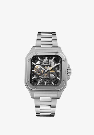 Vierkante automatische horloge met een transparante zwarte wijzerplaat die de interne werking toont. Roestvrijstalen kast en armband, zilveren accenten en markeringen.