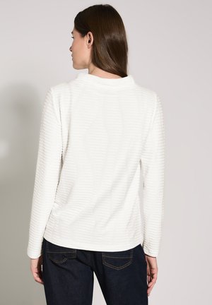Witte langelijf top met gestructureerde strepen, ronde halslijn en een ontspannen pasvorm. Gepaard met donkere jeans in een casual stijl.
